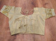 A pretty choli blouse in light gold soft tissue cotton with contrasting designs embroidered on the sleeves.  A choli is basically an Indian version of a crop top, traditionally worn with a saree or skirt but can also be paired with jeans or however suits you.  It has lining, is button up, has tie strings with pretty tassels at the back and short sleeves. It is available in size medium, which fits a 37-38 inch bust - with a few inches inseam - enough to adjust it up a little bigger should you need.  Please note that due to the nature of digital photography the colors may vary slightly in that they may be more vibrant or muted than the image. Transitional Gold Cotton Silk Blouse Piece, Designer Gold Cotton Silk Blouse Piece, Gold Cotton Silk Blouse With Traditional Drape, Gold Cotton Silk Choli With Cutdana, Gold Choli With Cutdana In Cotton Silk, Elegant Gold Cotton Silk Choli With Cutdana, Traditional Fitted Beige Saree, Gold Anarkali Blouse In Cotton Silk, Gold Anarkali Cotton Silk Blouse Piece