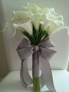 a bouquet of white flowers in a vase with a bow on the back of it