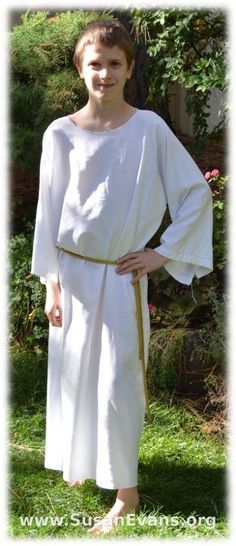 a woman in white dress standing on grass with her hands on her hips and one hand on her hip