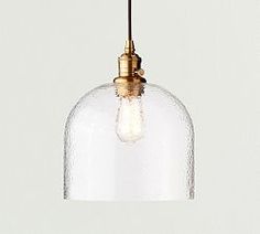 a clear glass pendant light hanging from a ceiling fixture with a gold metal fitting on the end