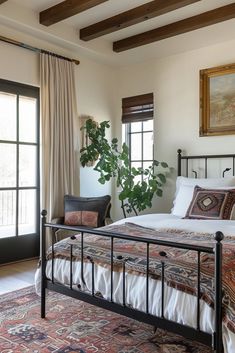 a bedroom with a bed, rugs and plants in the window sill next to it