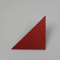 a red and white polka dot triangle on a gray background with the corner cut out