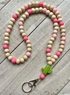 a pink and green beaded dog leash on a white wooden table with a green polka dot bow