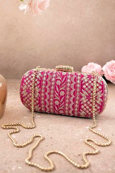 "Put together the perfect wedding look with our Mirai Embroidered clutch. This bag effortlessly delivers the Indian festive look. The luxe gold embroidery is a visual delight to the eyes. The gold tassels and the gold scallop lace add on to the grandeur of the bag. It's the perfect accessory for the bride to be who will be the center of attention.   Color: Pink with gold embroidery Dimensions (LxB): 8\"x4\" Handle length: 47\" Handle drop: 23\" Material: Embroidered poly silk, suede lining, golden metal clutch frame, golden metal sling. Features: metal lock closure, detachable metal sling." Luxury Wedding Clutch With Gold Embroidery, Luxury Gold Embroidered Clutch For Wedding, Rectangular Embroidered Evening Bag For Wedding, Rectangular Shoulder Bag For Receptions And Festivals, Gold Evening Bag With Handwork For Reception, Gold Embroidered Clutch For Festivals, Festive Embroidered Clutch Evening Bag, Designer Pink Clutch For Party, Elegant Bags For Festivals And Receptions