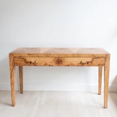 a wooden table sitting on top of a hard wood floor next to a white wall