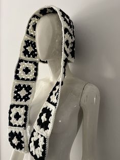 a white mannequin wearing a black and white scarf