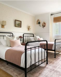 two beds in a bedroom with pink and white bedding