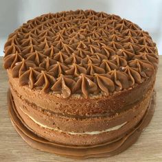 a cake with chocolate frosting on top is sitting on a wooden table next to other cakes