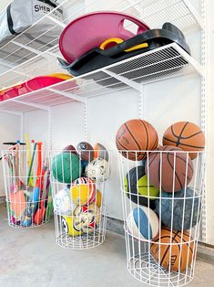 two baskets filled with basketballs and other sports items on top of a white shelf