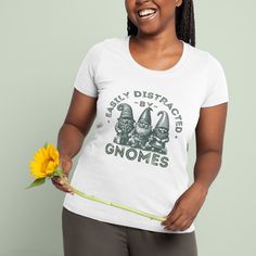 Love gardening and gnomes? This adorable T-shirt featuring a vintage-inspired design of three garden gnomes and the funny quote, "Easily Distracted by Gnomes" might be just right for you. Perfect for plant ladies, garden lovers, and gnome enthusiasts, this comfy and stylish T-shirt makes a great addition to any garden-themed outfit. Wear it while tending plants, relaxing outdoors, or as a casual everyday look. A unique gift for gnome lovers, gardening fans, and anyone who enjoys cute gardening humor and whimsical designs.