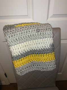 a crocheted blanket sitting on top of a chair next to a white door