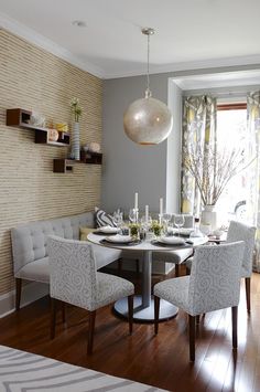 a dinning room table and chairs in front of a window with a striped rug on the floor