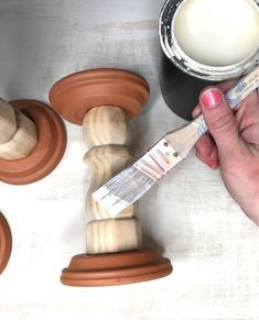 a person holding a paintbrush next to some clay molds and a wooden judge's gaven