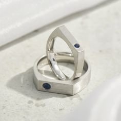 two wedding rings sitting on top of each other in front of a white countertop