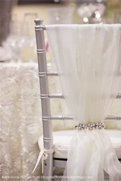 an image of a chair that is decorated with white fabric and pearls on the back