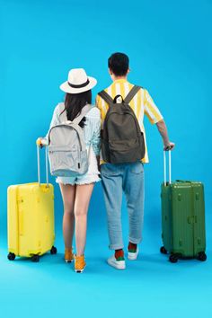 a man and woman are walking with suitcases on wheels, looking at each other