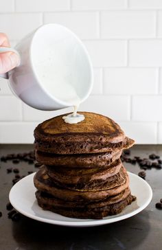 a stack of chocolate pancakes being poured with milk