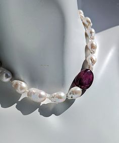 Introducing "Romancing the Stone" Pearl and Ruby Necklace crafted with love from my Oregon studio.Adorn yourself with the exquisite elegance of luxurious white baroque pearls. One smooth and tumbled large natural Ruby designed to be worn on the left shoulder. Small freshwater pearls are included and reveal themselves between each of the large pearls and ruby bead.The piece is secured with a 14 Karat gold hook and eye clasp, showcasing the artist's signature tag as a mark of authenticity and craftsmanship.The pearls, ranging from 12-16mm, boasts a luster that elevates the beauty of the necklace. Measuring 18.5" in length, this statement piece is sure to turn heads and leave a lasting impression wherever you go.For those who desire a complete ensemble, matching earrings are also available in White Baroque Pearl Necklace With Gemstone, Handmade White Baroque Pearl Necklace, White Briolette Pearl Necklace, White Baroque Pearl Necklace For Formal Occasions, Luxury White Baroque Pearl Necklace, Formal Handmade Baroque Pearl Necklace, Romancing The Stone, Glow Jewelry, Baroque Pearl Necklace