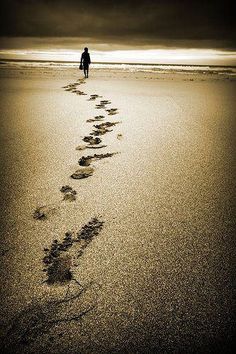 a person walking on the beach with footprints in the sand