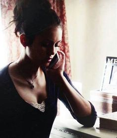 a woman talking on her cell phone in front of a desk with an open laptop