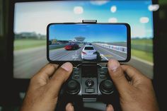 a person holding a game controller in front of a tv with a car on the screen