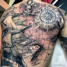 a man's back with a compass and ship tattoo on his upper half sleeve