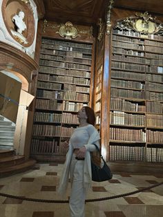 a woman standing in front of a library filled with books