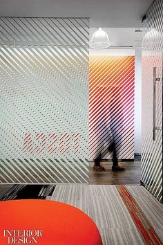 the interior design magazine cover shows a person walking in front of colorful wallpapers