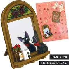 a wooden mirror with two black cats in front of it and a pink box behind it