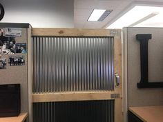 an office cubicle with a metal door and clock on the wall