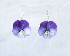 purple and white flower earrings hanging from hooks