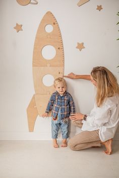 a woman and child are standing in front of a wall with a rocket ship on it