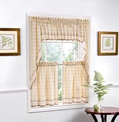 a living room with a table and two windows covered in curtained valances