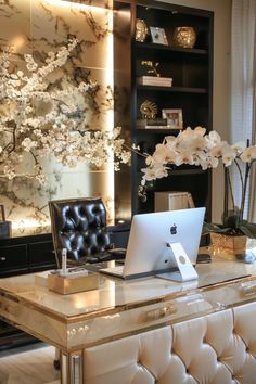 a laptop computer sitting on top of a desk next to a vase filled with flowers