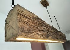 a light fixture made out of wood with chains hanging from it's sides and two lights on each side