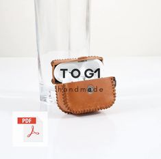 a cell phone in a leather case next to a tall glass with the text top1 on it