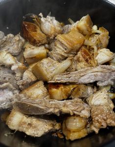 meat and onions cooking in a pan on the stove top with oil coming from it