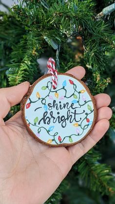 someone is holding up a christmas ornament that says shine bright with lights on it