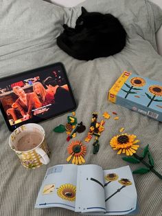 an open book on a bed with sunflowers and other items