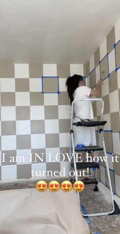 a woman is painting the walls in a room with white and gray checkered tiles