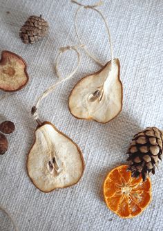 an orange slice and some pine cones on a white table cloth with twine cord