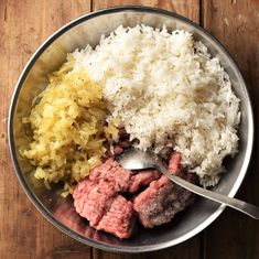 a metal bowl filled with rice and meat