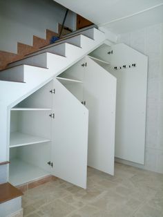 an empty room with white walls and open shelving units on the bottom floor, next to a stair case