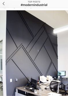 an office area with desks, chairs and a large black wall in the background