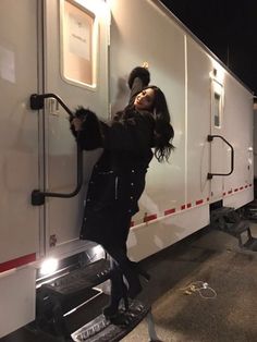 a woman standing on the side of a horse trailer with her hands in the door