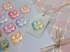 two tags with different designs on them sitting next to some other items that are wrapped in ribbon