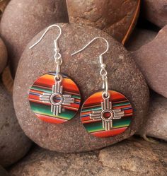 Zia Round Serape Earrings, New Mexico Serape Earrings, Southwestern Earrings, Western Earrings, Zia Jewelry, New Mexico Jewelry.  These lightweight earrings are perfect statement of the Southwest.  Earring is a lightweight wood printed with a vibrant serape print.  Final touch to adorn these precious earrings is a stainless-steel Zia charm.  These will for sure be your favorite earrings.  Perfect with any outfit and so light you won't even remember you are wearing them.  Get your today, they com Handmade Southwestern Earrings For Gift, New Mexico Jewelry, Handmade Southwestern Metal Earrings, Serape Earrings, Southwest Earrings, Nickel-free Southwestern Teardrop Earrings For Gifts, Southwestern Earrings, Southwestern Hand-tooled Earrings As Gift, Nickel-free Southwestern Style Festival Earrings