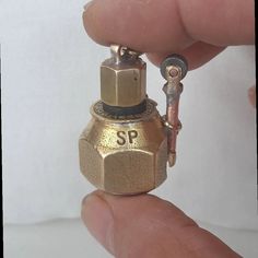 a tiny gold colored bottle shaped like a keychain with the word sp on it