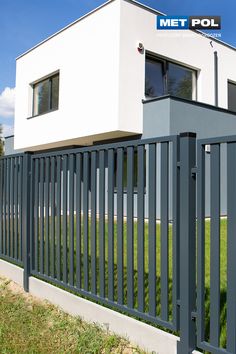 a white house behind a metal fence in the grass