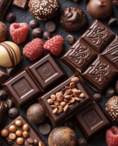 many different types of chocolates and nuts are on the table together, including raspberries